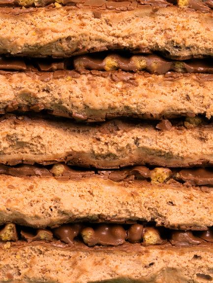 Stacked Barebells Choco Champ protein bars showing layers of crispy cookie and chocolate filling with peanut pieces