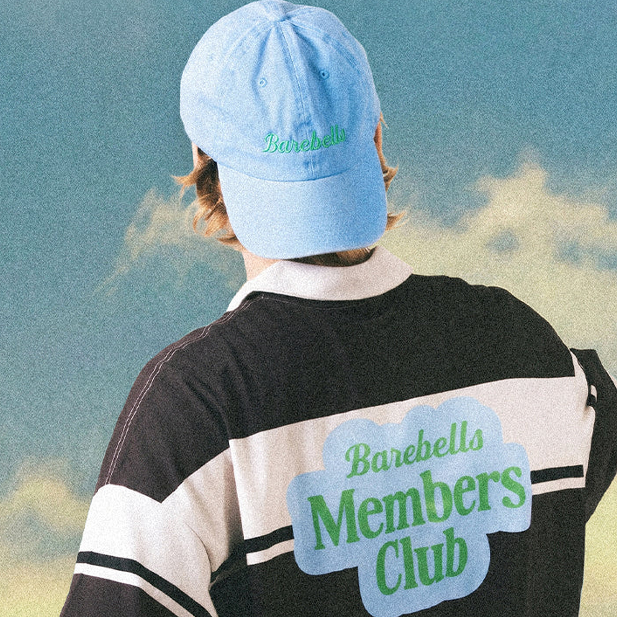 Person wearing light blue Barebells cap and color-block jacket with Members Club patch